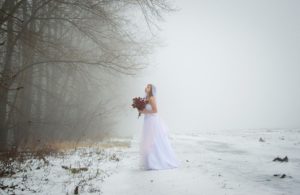 Bride standing alone in snow